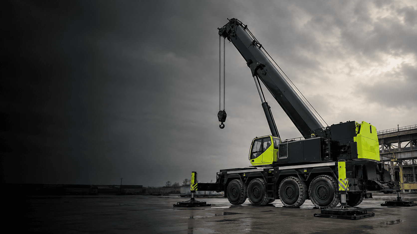 Illustrative black and lime mobile crane on an industrial site beneath an overcast sky.